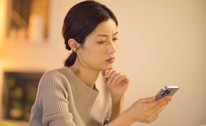 スマホを見ながら悩んでいる女性