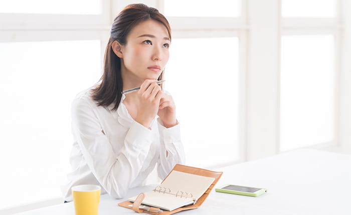 考え事をしながらメモを取る女性